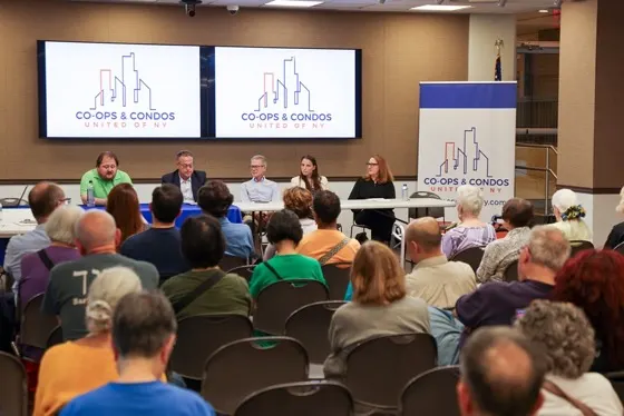 Panelists seated at Co-ops and Condos United branded tables addressing a full room of shareholders at Southbridge Towers